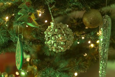 Bu resim, çok güzel dekore edilmiş bir Noel ağacının, canlı yeşil ışıklarla süslenmiş, yumuşak bir şekilde parıldayan bir resmini içeriyor.