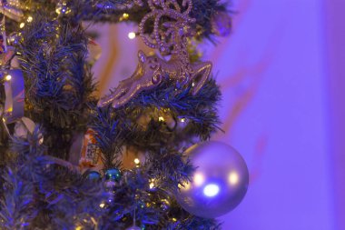 Göz kamaştırıcı mor ışıklar ve zarif süslemelerle süslenmiş güzel dekore edilmiş bir Noel ağacının detaylı bir görüntüsü.