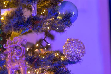İşte güzel dekore edilmiş bir Noel ağacının yakından görüntüsü. Güzel mor ışıklar ve çeşitli dekorasyonlarla süslenmiş.
