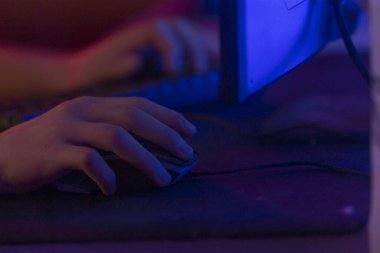 Bir birey, dijital arayüzle bağlantılı bir bilgisayar ekranının önünde otururken aktif olarak bir bilgisayar faresi kullanıyor