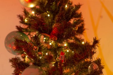 Kırmızı ve altın süslerle süslenmiş güzel dekore edilmiş bir Noel ağacı, yanıp sönen ışıklar, ve herkesin eğlenmesi için bayram neşesi.