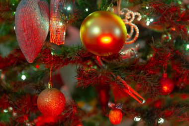 Parlak kırmızı ve altın süslemelerle süslenmiş güzel dekore edilmiş bir Noel ağacının detaylı bir görüntüsü.