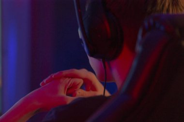 Kulaklık takan bir adam aktif olarak video oyunu oynamakla meşgul, interaktif dijital deneyime kendini kaptırıyor.