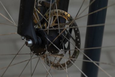 Görüntü, şehir arka planına karşı kurulmuş bir tekerlek merkezinin yanında bir bisiklet diski frenini gösteriyor.