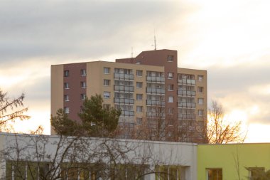 Gün batımında, arka planda yemyeşil ağaçlarla çevrili, görkemli bir apartman.