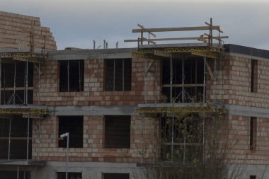 Dayanıklı bir tuğla bina şu anda yapım aşamasında ve işçilere görevlerinde yardım etmek için üzerine iskele döşenmiş durumda.