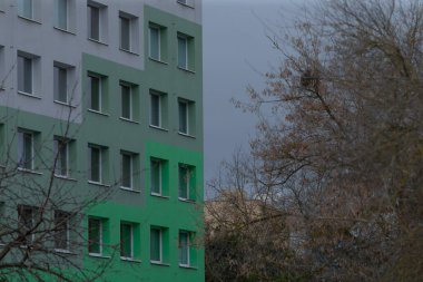 Çarpıcı bir modern bina, arka planda gür ağaçlarla çevrili canlı yeşil aksanlar sergiliyor.