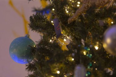 Bu, çok güzel süslenmiş bir Noel ağacının yakın bir görüntüsü. Etrafında çeşitli süslemeler ve parıldayan ışıklar var.