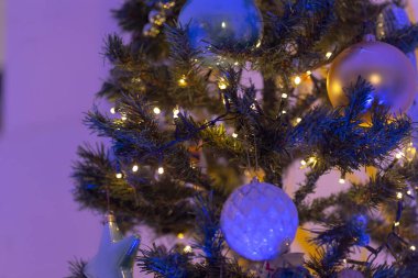 Bu resim, parlak ışıklarla birlikte çarpıcı mavi ve altın süslemeler içeren güzel süslenmiş bir Noel ağacının yakın çekim görüntüsünü yakalar.