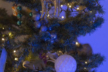 İşte güzel dekore edilmiş, parlak mavi ışıklar ve çeşitli dekorasyonlarla süslenmiş Noel ağacının yakın bir görüntüsü.