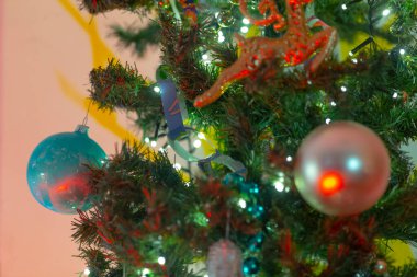 İşte güzel dekore edilmiş Noel ağacının detaylı bir görüntüsü şenlikli süsler ve parlak ışıklarla süslenmiş.