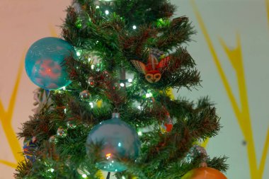 Renkli balonlarla süslenmiş güzel bir Noel ağacı ve dallarını süsleyen bir dizi hoş süslemeler.