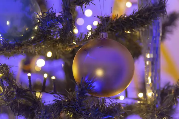 Burada, dallarından zarif bir şekilde sarkan canlı mor bir süslemeyle süslenmiş güzel dekore edilmiş bir Noel ağacının yakın görüntüsü var.