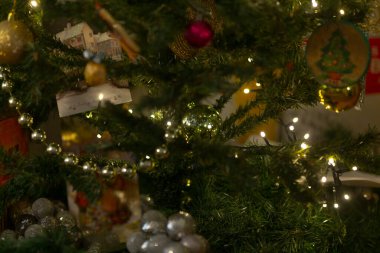 Bu, çeşitli parıltılı süslemeler ve renkli ışıklarla süslenmiş güzel dekore edilmiş bir Noel ağacının güzel bir yakın plan görüntüsü, sezonun neşeli ruhunu yansıtıyor.