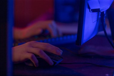 Bir kişi bir bilgisayar ekranının önünde otururken aktif olarak bir bilgisayar faresi ve klavyesi kullanıyor, arayüze bağlanıyor