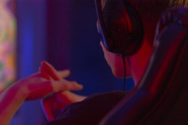 Bir adam, kulaklık takmış, oyun atmosferini arttıran karanlık bir odada tek başına otururken bir video oyununa dalmış.