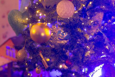 Güzel süslenmiş bir Noel ağacı pırıl pırıl mor ışıklar ve zarif altın süslemelerle süslenmiş, neşeli bir atmosfer yaratıyor.