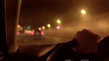 Sürücülerin perspektifinde, bulanık kentsel geçmişle işaretlenmiş büyüleyici bir gece yol sahnesi yer alıyor.