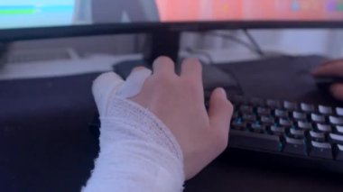 Bandaja sarılı bir el monitörün önündeki bilgisayar klavyesinin yanına yerleştirilir.
