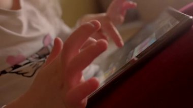 Bir çocuğun küçük eli, evdeki sıcak ve rahat ortamda parlak bir tabletle meşgul.