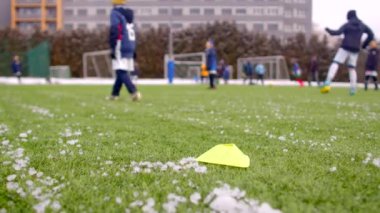 Bokeh etkisi, sezon boyunca sahada antrenman yapan çocuklar. Genç futbolcular karlı bir alanda antrenman yapıyorlar. Kozalakları tatbikat ve egzersiz için kullanıyorlar.