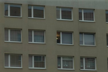 Birçok penceresi olan, kentsel yaşam ve modern tasarımı yansıtan çok katlı bir apartmanın büyüleyici bir görüntüsü.