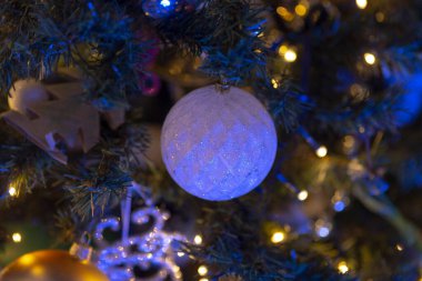 Zarif bir süs, güzel dekore edilmiş bir Noel ağacına asılı. Güzel mavi ışıkları var.