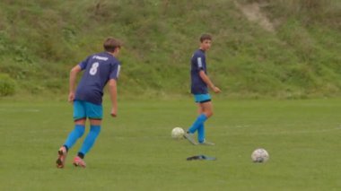 İki genç futbolcu verimli, yeşil çimenli bir sahada özenle antrenman yaparken aralarında ustalıkla bir futbol topu oluşturuyorlar, atletik yeteneklerini geliştiriyorlar CZ, Kralupy, 12.10.24