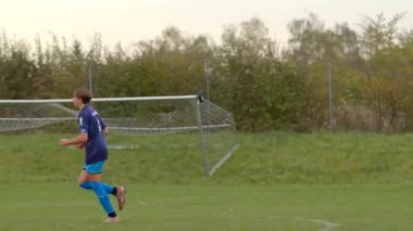 Parlak mavi üniformalı futbolcu çimlerin üzerinde enerjik bir şekilde koşarken hakem adil bir oyun ve tüm CZ, Kralupy, 12.10.24 için rekabetçi ama eğlenceli bir maç sunuyor.