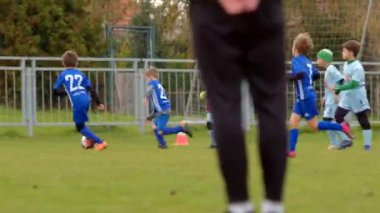 Genç oyuncular, CZ, Unhost, 10.10.24 gibi çeşitli arka plan aktivitelerinin ortasında sahada enerjik bir şekilde bir futbol maçına katılıyorlar.