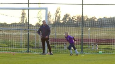 Genç bir çocuk, güneşli bir futbol sahası olan CZ, Kladno, 18.10.24 'te tecrübeli bir yetişkin koçtan eğitim alıyor.