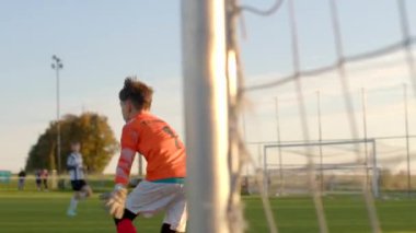 Turuncu forma giyen bir genç futbolcu yoğun bir şekilde CZ, Kladno, 18.10.24 'te oynanan maça odaklanmış durumda.
