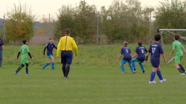 Genç futbolcular, hakemlerin gözetimi altında enerjik bir şekilde yarışan çimenli bir sahada yeteneklerini sergiliyorlar. Renkli üniformaları takım çalışması ve heyecan verici gençlik sporları CZ, Kralupy, 12.10.24