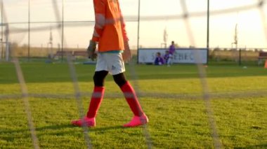 Genç bir futbolcu, golü korumak için yoğun bir şekilde yeşil bir sahada antrenman yapar ve oyuncuların CZ, Kladno, 1.10.24 becerilerini sergilemeleri için güzel bir zemin sağlar.