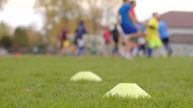 Bir grup hevesli genç futbolcu, spor yolculukları için çok önemli oyun becerilerini sergileyerek koni ve yetenek tatbikatlarıyla yoğun bir şekilde antrenman yapıyorlar.