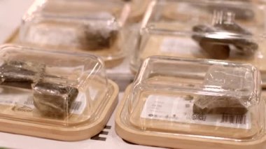Organize bir ekran, şeffaf kaplarda çeşitli paketlenmiş bitkisel ürünler sunar, eşsiz tasarımlarını ve canlı renklerini göstererek, izleyenler için büyüleyici bir görsel deneyim yaratır.
