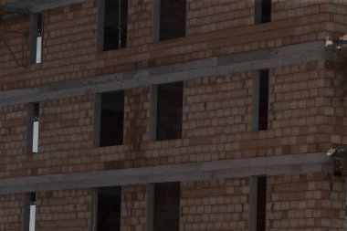 Şu anda inşa halinde olan çok katlı tuğla bina, geniş doğal ışığa olanak sağlayan çok sayıda açık pencereye sahip.