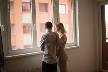 Bir çift pencerenin yanında duruyor, canlı bir şehir zeminine sahip modern bir iç mekan yansıtıyor.