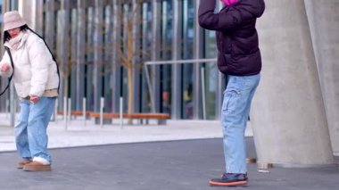 İki birey, modern mimari ile canlı bir şehir ortamında güvenli bir şekilde poz veriyorlar.