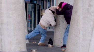 Şehir enerjisiyle dolu canlı bir şehir sahnesinde, beton sütunların yanında iki insan neşeyle etkileşime geçiyor.