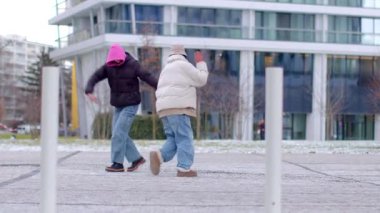 İki birey, modern mimari tasarımların yer aldığı kış şehirlerinde rahatça yürüyor.