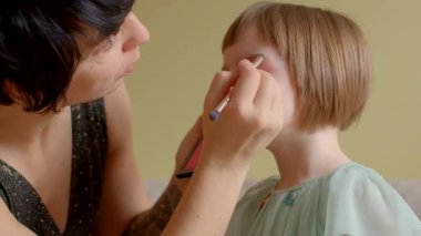 Yetişkinler, çocuklarına evlerinde makyaj yaparken yardım ederler.