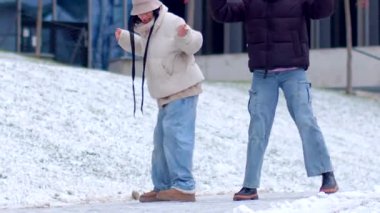 Çocuklar mutlu bir şekilde dışarıda karlı bir günün tadını çıkarıyorlar. Canlı bir şehir ortamında oynayıp eğleniyorlar.