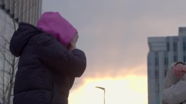 Alacakaranlıkta canlı bir şehir zeminine karşı neşeli bir jest oyunu oynayan iki kişi.