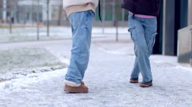Karlı bir sokakta rahat kıyafetler giymiş iki kişi tesadüfen birlikte dolaşıyorlar.