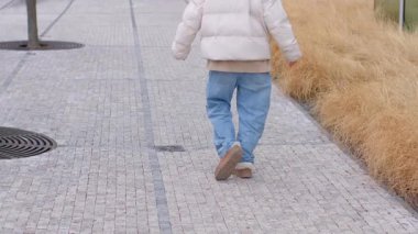 Bireysel bir rahatça asfalt bir yolda yürüyor, arka planda canlı yemyeşil çimenler genişliyor.