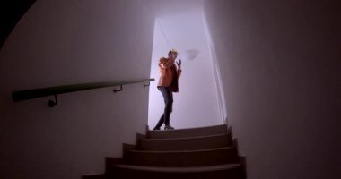 Bir birey zarif bir şekilde aydınlatılmış bir merdivenden iner, hareketin özünü gözler önüne serer.