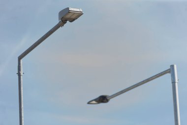 Yapıları ve tasarımları için mükemmel bir zemin sağlayan açık mavi gökyüzüne karşı iki sokak lambası güzel bir şekilde yerleştirilmiştir.