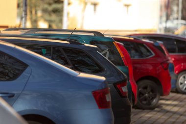 Geniş bir otoparkta park edilmiş, farklı renkler ve uygun alanları kaplayan araçlar var.