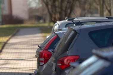 Yoğun bir kaldırım boyunca yan yana park edilmiş uzun bir sıra araba, bunu tipik bir şehir manzarası haline getiriyor.